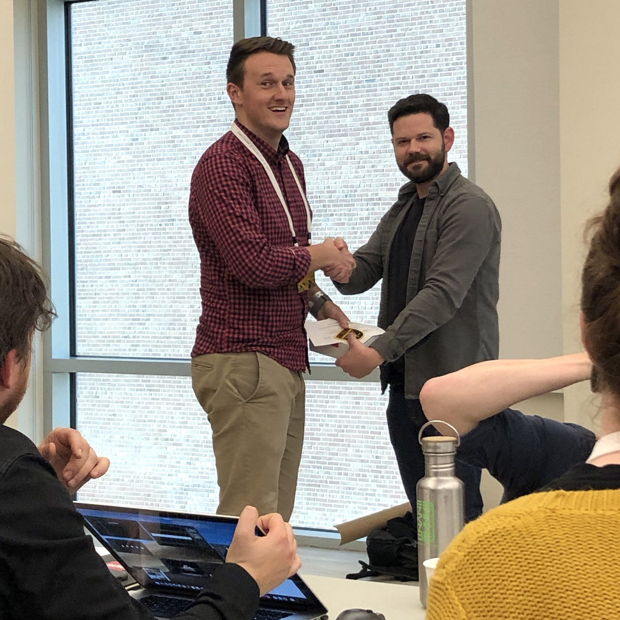Austin and Nathan shaking hands at a playful, low-key course completion ceremony